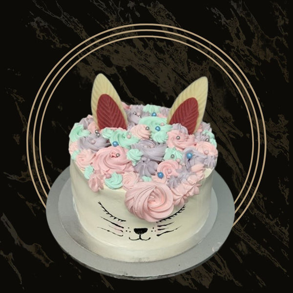 Fun design cake with pink frosting and edible figures from The Bakers Shop in Birmingham