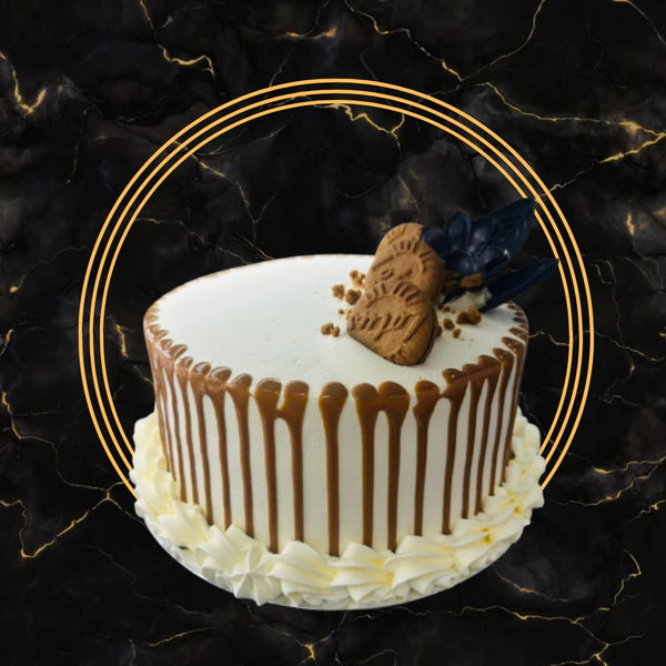 Lotus Biscoff drip cake with creamy frosting and biscuit topping on a black marble background