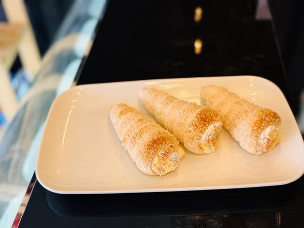 Three rolled pastries on a white plate with a blurred background